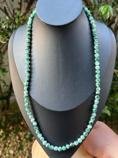 Woman wearing a 22-inch elegant natural Grade A jade bead necklace with a gold-tone twist clasp