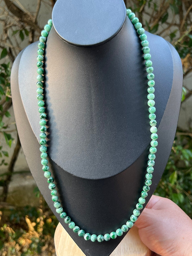 Woman wearing a 22-inch elegant natural Grade A jade bead necklace with a gold-tone twist clasp
