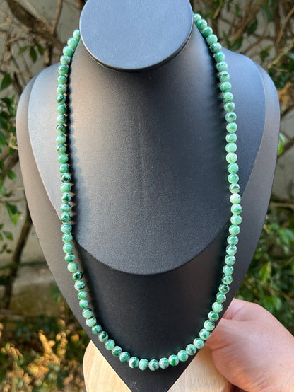 Woman wearing a 22-inch elegant natural Grade A jade bead necklace with a gold-tone twist clasp