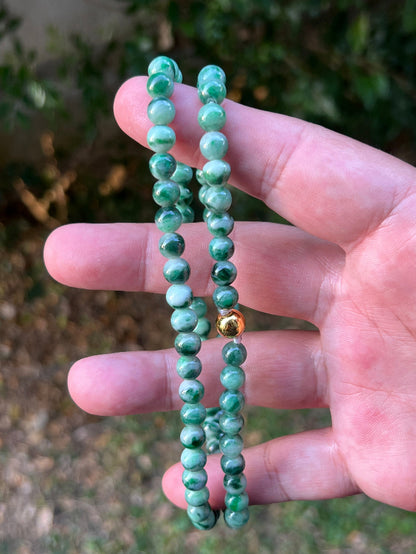 Woman wearing a 22-inch elegant natural Grade A jade bead necklace with a gold-tone twist clasp