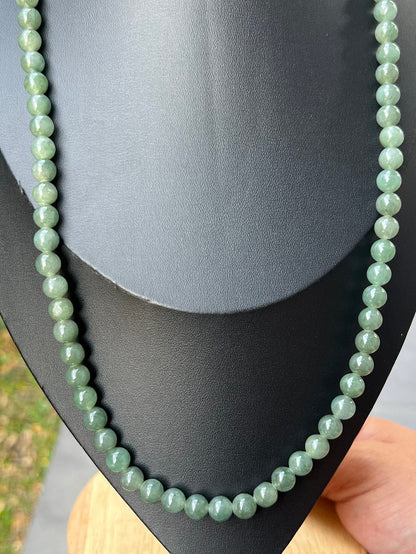 Woman wearing a 23-inch elegant natural Grade A jade bead necklace with a gold-tone twist clasp
