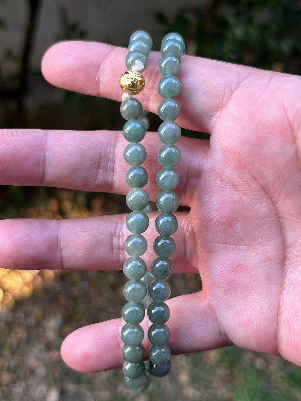 Woman wearing a 23-inch elegant natural Grade A jade bead necklace with a gold-tone twist clasp