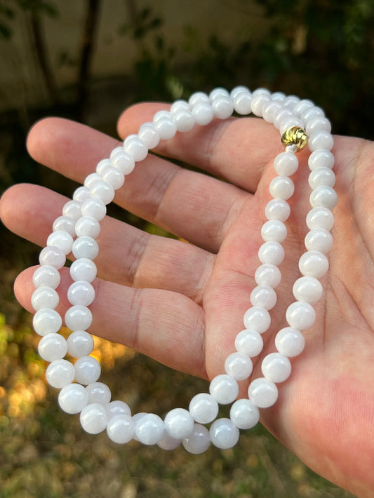 Woman wearing a 23-inch elegant natural Grade A jade bead necklace with a gold-tone twist clasp