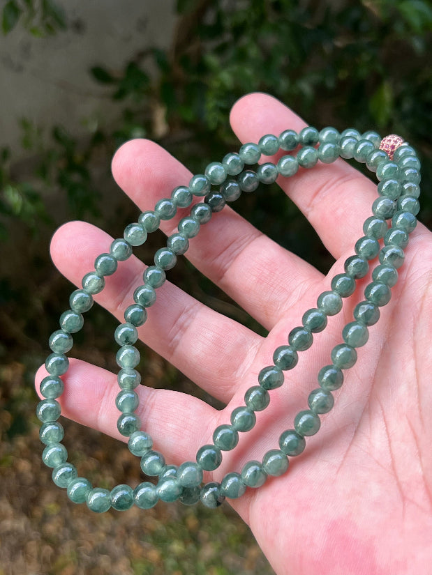 Woman wearing a 23-inch elegant natural Grade A jade bead necklace with a red-tone twist clasp