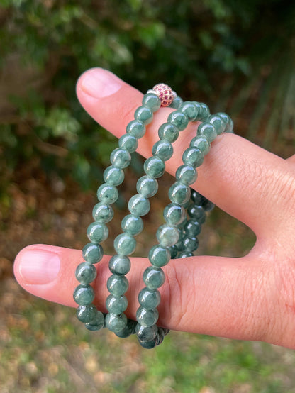 Woman wearing a 23-inch elegant natural Grade A jade bead necklace with a red-tone twist clasp