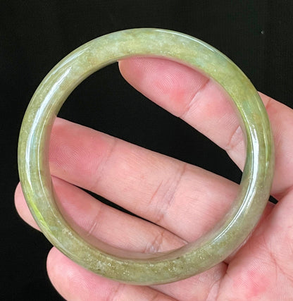 Close-up of fine crystalline texture and vibrant forest green hues on icy apple green and honey white jadeite bangle