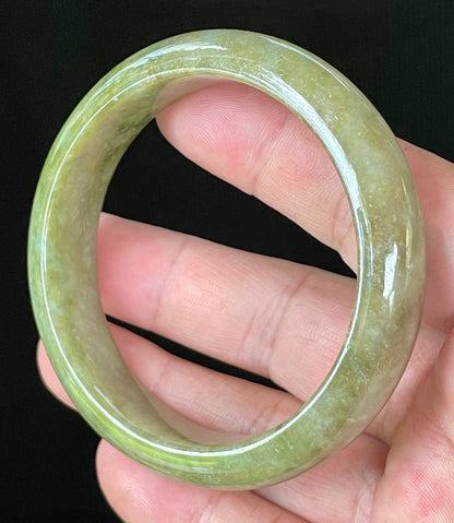 Close-up of fine crystalline texture and vibrant forest green hues on icy apple green and honey white jadeite bangle