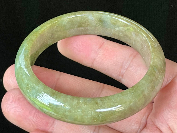 Close-up of fine crystalline texture and vibrant forest green hues on icy apple green and honey white jadeite bangle