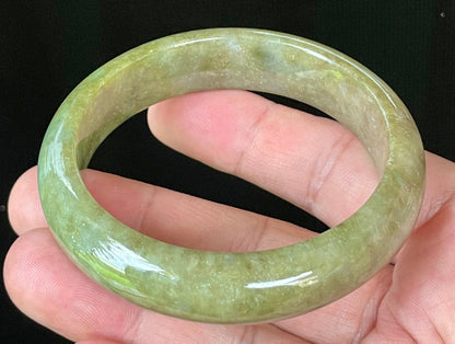 Close-up of fine crystalline texture and vibrant forest green hues on icy apple green and honey white jadeite bangle