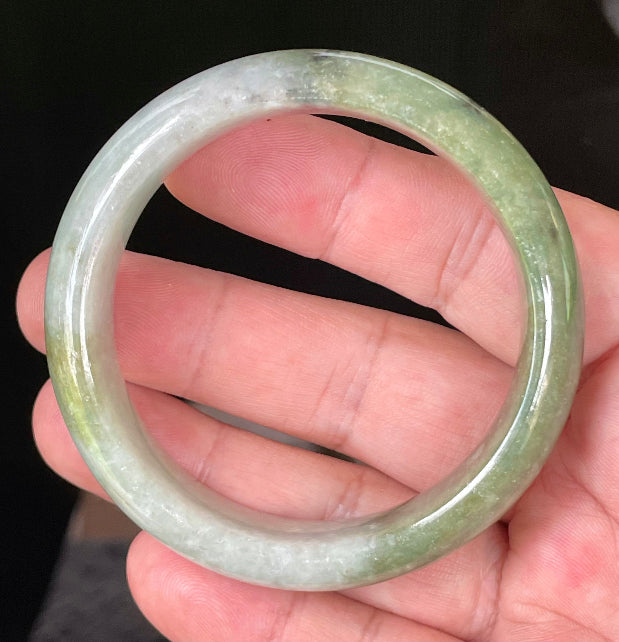 Close-up of fine crystalline texture and distinctive black accents on icy apple green and greyish white jadeite bangle