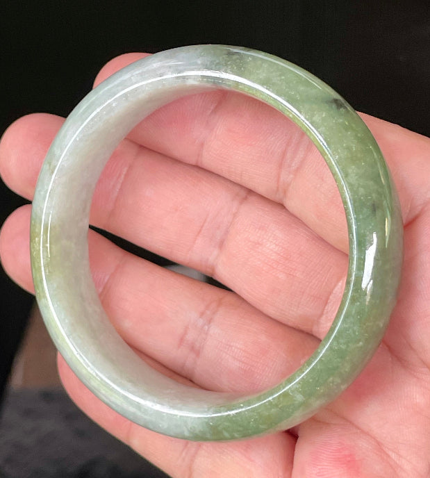 Close-up of fine crystalline texture and distinctive black accents on icy apple green and greyish white jadeite bangle