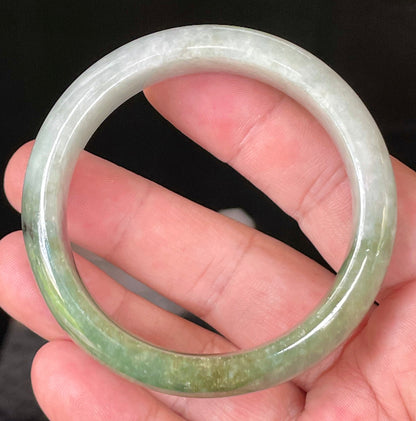 Close-up of fine crystalline texture and distinctive black accents on icy apple green and greyish white jadeite bangle