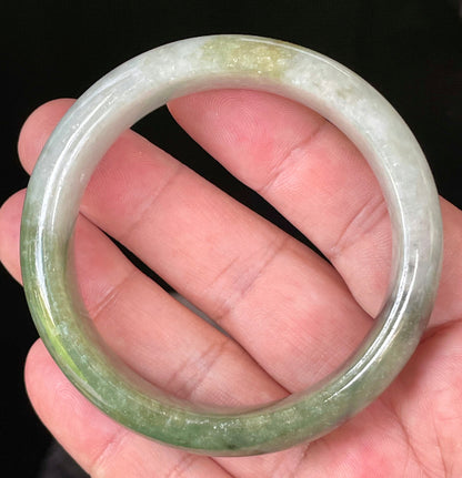Close-up of fine crystalline texture and distinctive black accents on icy apple green and greyish white jadeite bangle