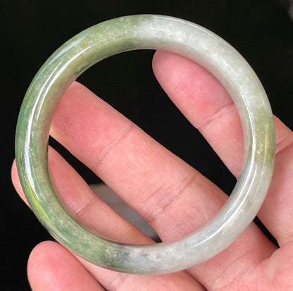 Close-up of fine crystalline texture and distinctive black accents on icy apple green and greyish white jadeite bangle