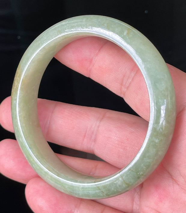 Close-up of fine crystalline texture and honey hues on icy apple green and milky white jadeite bangle