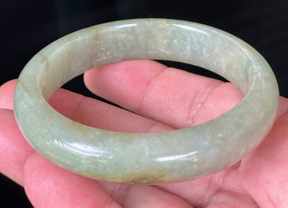 Close-up of fine crystalline texture and honey hues on icy apple green and milky white jadeite bangle