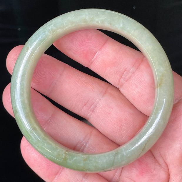 Close-up of fine crystalline texture and honey hues on icy apple green and milky white jadeite bangle