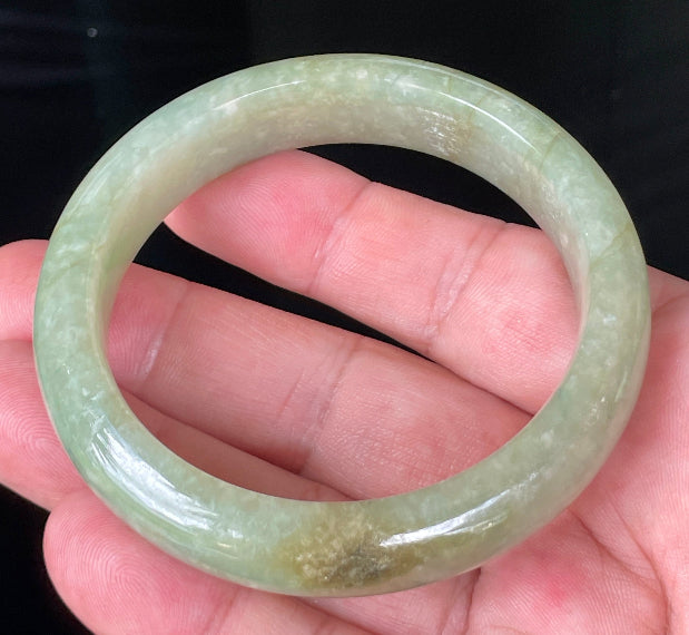 Close-up of fine crystalline texture and honey hues on icy apple green and milky white jadeite bangle