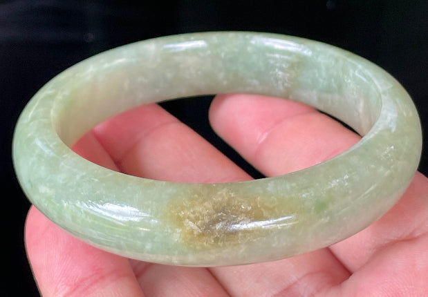 Close-up of fine crystalline texture and honey hues on icy apple green and milky white jadeite bangle