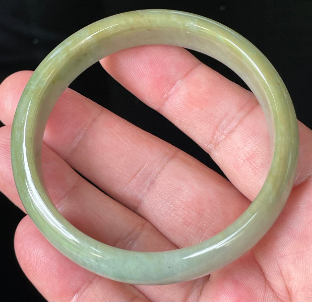 Close-up of fine crystalline texture and warm honey hues on icy bluish white jadeite bangle