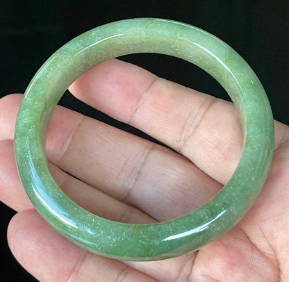 Close-up of fine crystalline texture and warm honey hues on icy apple green and white jadeite bangle