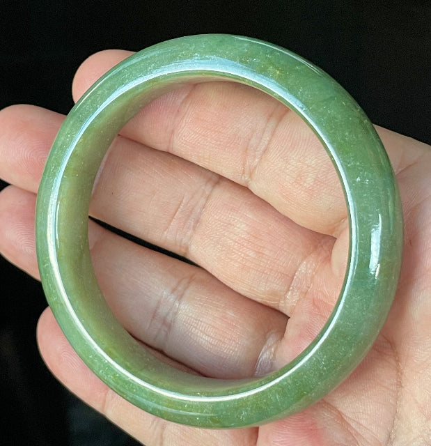 Close-up of fine crystalline texture and warm honey hues on icy apple green and white jadeite bangle