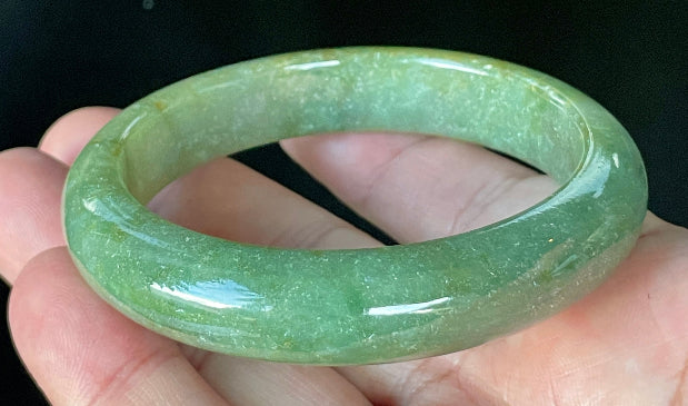 Close-up of fine crystalline texture and warm honey hues on icy apple green and white jadeite bangle
