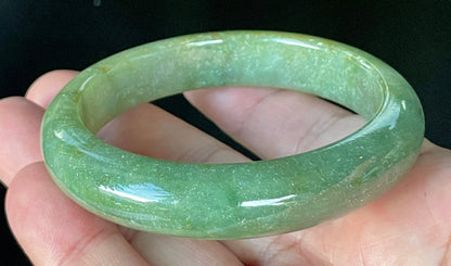 Close-up of fine crystalline texture and warm honey hues on icy apple green and white jadeite bangle