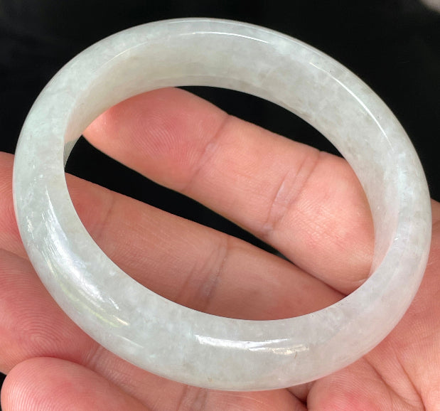 Close-up of fine crystalline texture and distinctive imperial green dots on icy apple green and white jadeite bangle