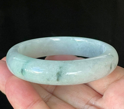 Close-up of fine crystalline texture and delicate green flecks on icy greyish white jadeite bangle