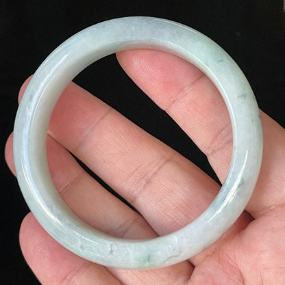 Close-up of fine crystalline texture and delicate green flecks on icy greyish white jadeite bangle