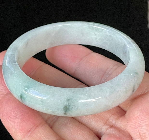 Close-up of fine crystalline texture and delicate green flecks on icy greyish white jadeite bangle