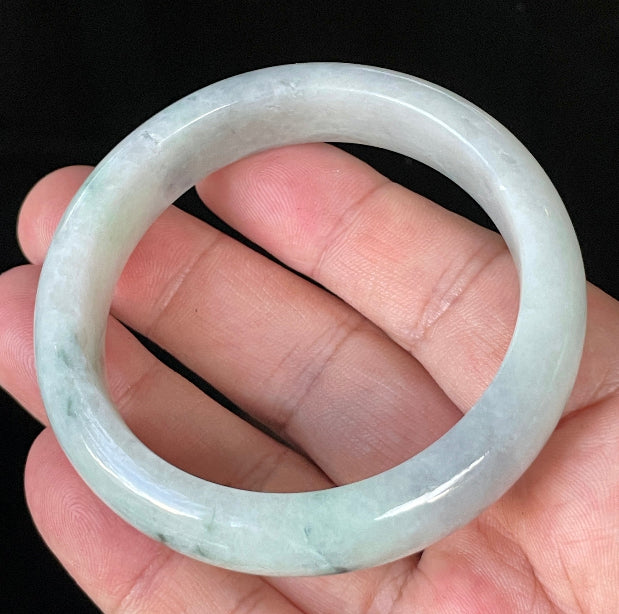 Close-up of fine crystalline texture and delicate green flecks on icy greyish white jadeite bangle