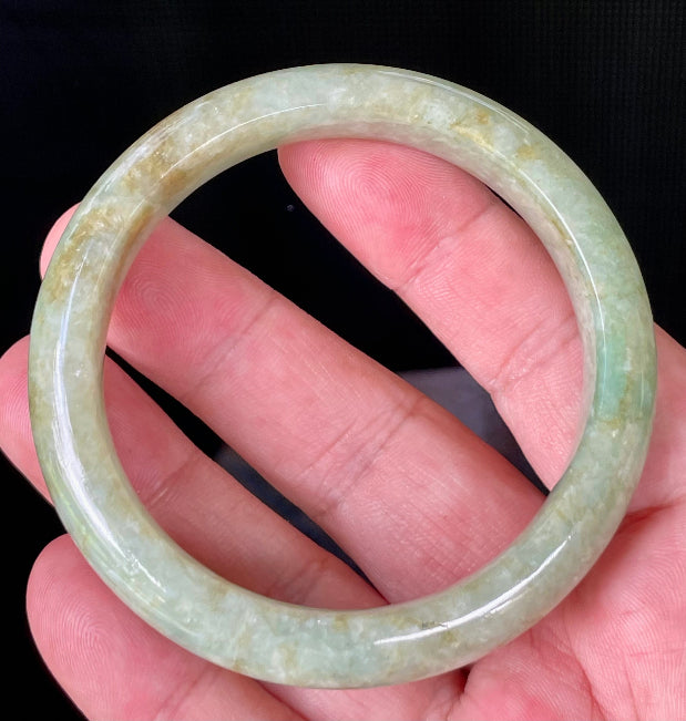 Close-up of fine crystalline texture and moss in the snow effect on icy apple green and milky white jadeite bangle