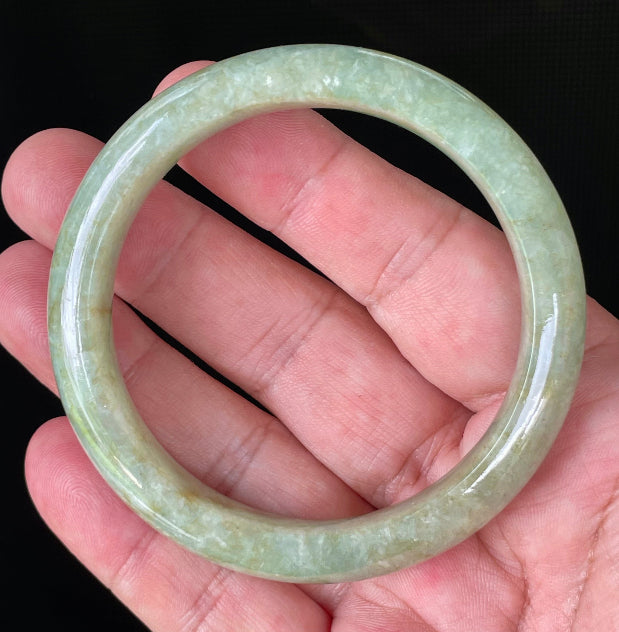 Close-up of fine crystalline texture and moss in the snow effect on icy apple green and milky white jadeite bangle