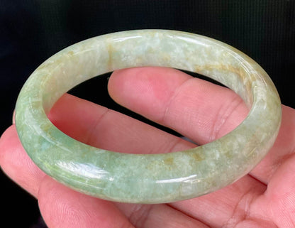 Close-up of fine crystalline texture and moss in the snow effect on icy apple green and milky white jadeite bangle