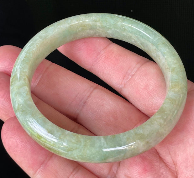 Close-up of fine crystalline texture and moss in the snow effect on icy apple green and milky white jadeite bangle