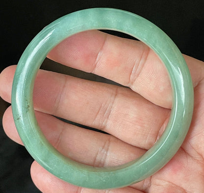 Close-up of fine crystalline texture and vivid imperial green hues on icy apple green jadeite bangle