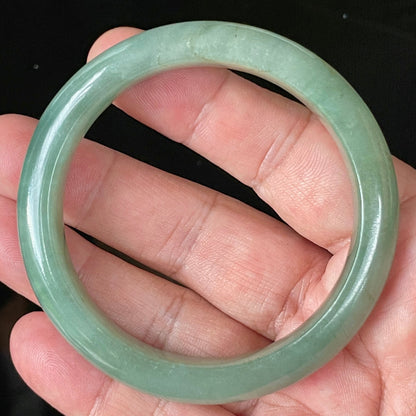 Close-up of fine crystalline texture and vivid imperial green hues on icy apple green jadeite bangle