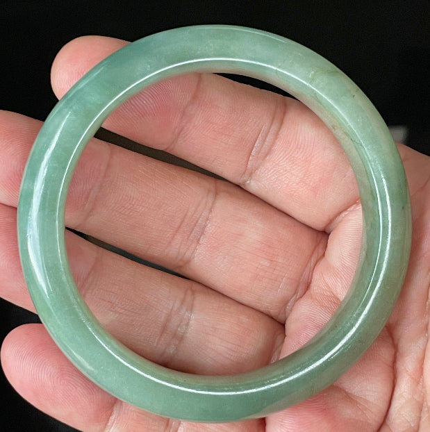Close-up of fine crystalline texture and vivid imperial green hues on icy apple green jadeite bangle
