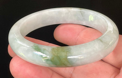 Close-up of fine crystalline texture and beautiful moss green swirls on icy apple green and white jadeite bangle