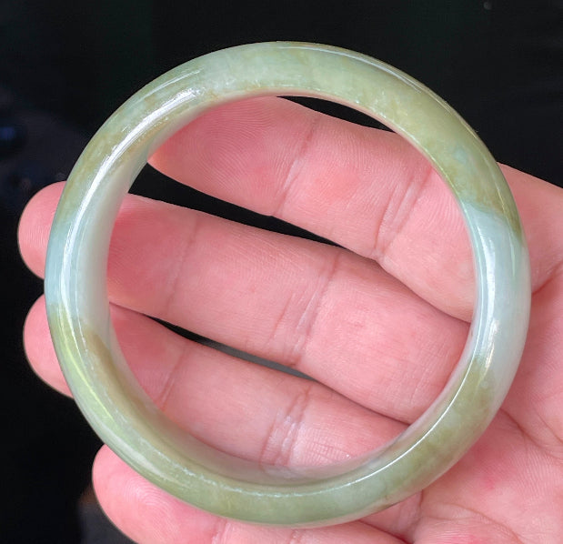 Close-up of fine crystalline texture and serene moss green hues on icy apple green and bluish white jadeite bangle