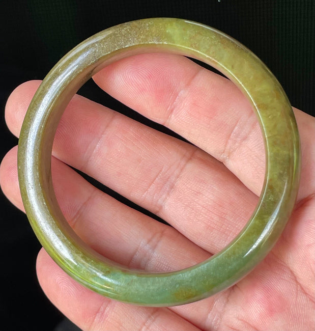 Close-up of fine crystalline texture and warm honey red patterns on translucent apple and moss green jadeite bangle