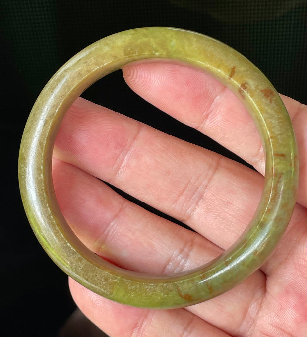 Close-up of fine crystalline texture and warm honey red patterns on translucent apple and moss green jadeite bangle