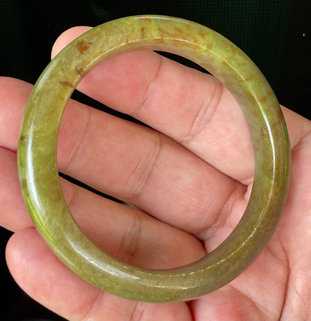 Close-up of fine crystalline texture and warm honey red patterns on translucent apple and moss green jadeite bangle
