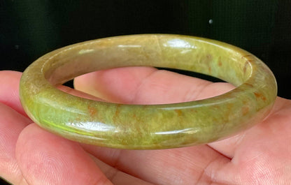 Close-up of fine crystalline texture and warm honey red patterns on translucent apple and moss green jadeite bangle