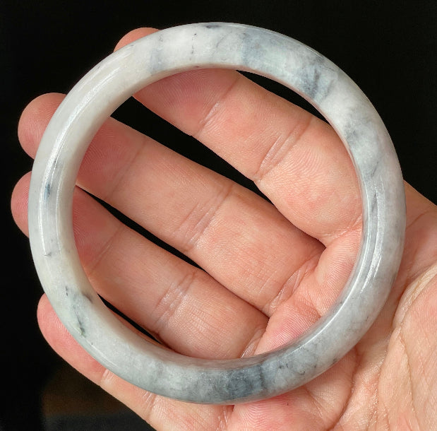 Close-up of fine crystalline texture and subtle honey hues on icy grey and milky white jadeite bangle