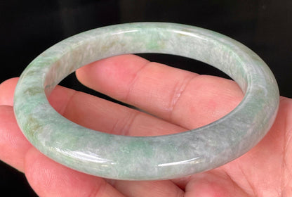 Close-up of fine crystalline texture and imperial green hues on icy greyish apple green jadeite bangle