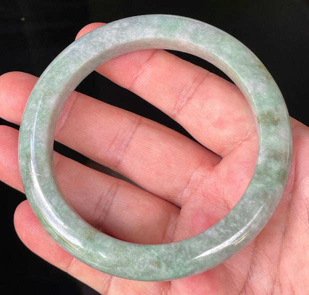 Close-up of fine crystalline texture and imperial green hues on icy greyish apple green jadeite bangle