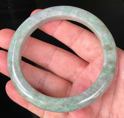 Close-up of fine crystalline texture and imperial green hues on icy greyish apple green jadeite bangle